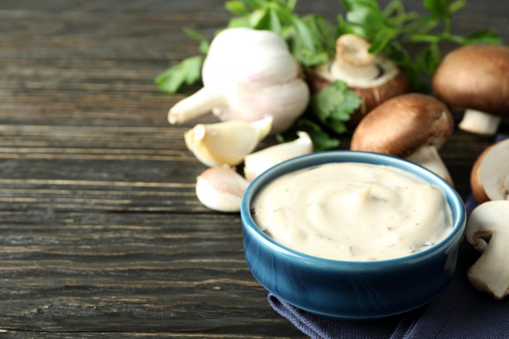 Thick portobello mushroom sauce being poured over a grilled steak, adding a creamy, savory finish